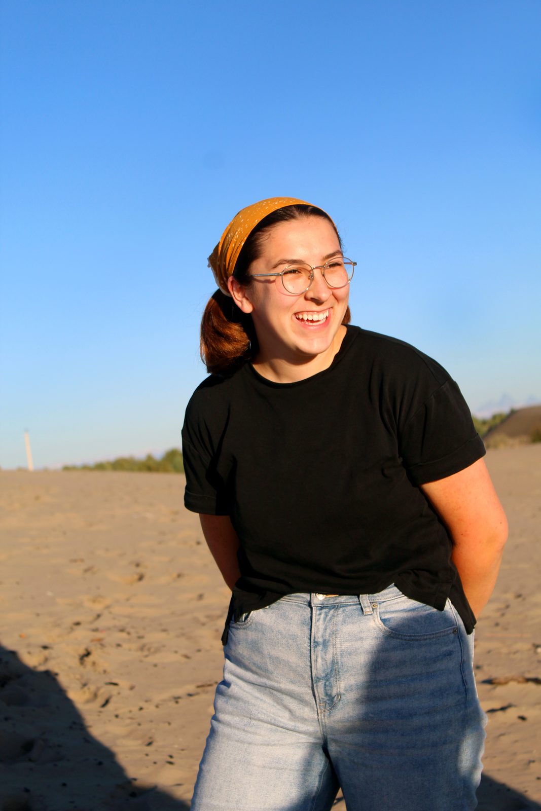 Portrait of a woman in a black tee and headband standing on sand dunes